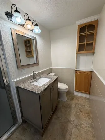a bathroom with a granite countertop sink and a toilet