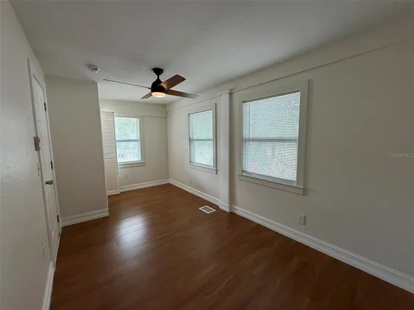 an empty room with wooden floor and windows