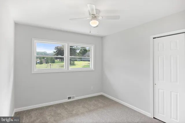an empty room with windows and ceiling fan