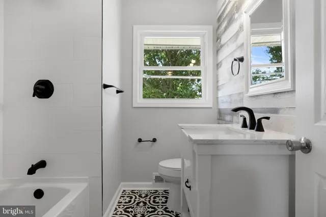 a bathroom with a granite countertop sink a toilet and a window