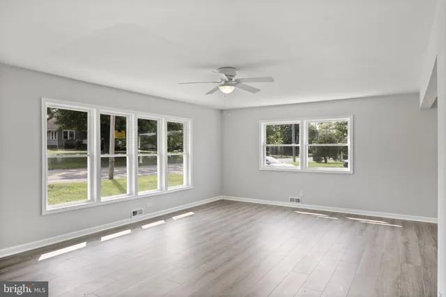 a view of an empty room with a window and wooden floor
