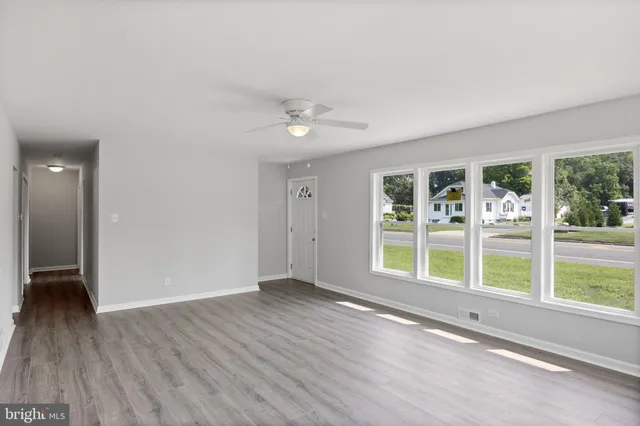 a view of an empty room with a window and wooden floor