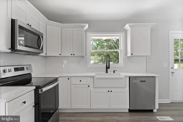 a kitchen with white cabinets appliances and a window
