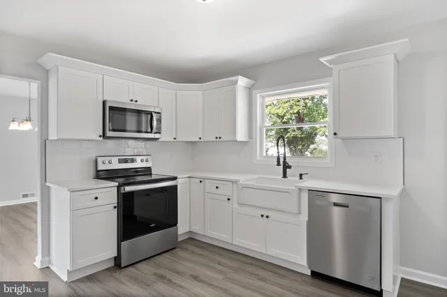 a kitchen with white cabinets appliances a sink and a window