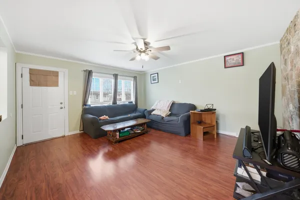 a living room with furniture flat screen tv and a ceiling fan