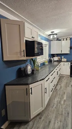 a kitchen with granite countertop a sink stove and microwave