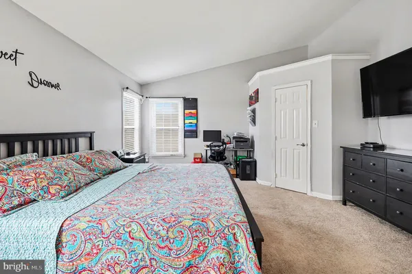 a bedroom with a bed and a flat tv screen on dresser