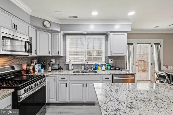 a kitchen with stainless steel appliances granite countertop a stove top oven a sink a dining table and chairs