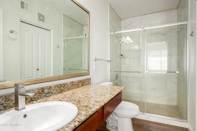 a bathroom with a granite countertop sink toilet and shower
