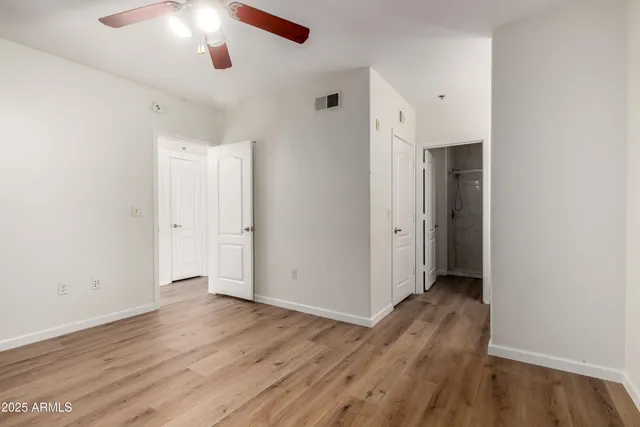 an empty room with wooden floor and a ceiling fan
