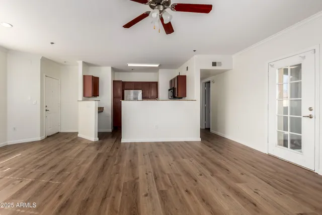 a view of a kitchen with a fridge wooden floor and a ceiling fan