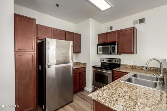 a kitchen with stainless steel appliances granite countertop a refrigerator stove a sink and a microwave