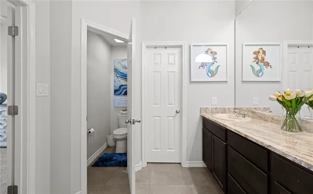 a bathroom with a granite countertop sink a toilet and painting on the wall