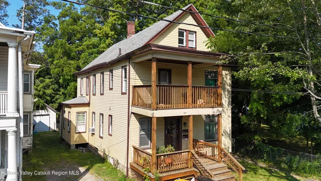 a view of small white house with a small yard and large trees