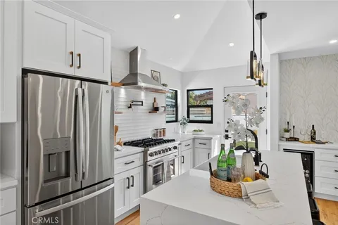 a kitchen with stainless steel appliances a refrigerator a stove a sink a dining table and chairs