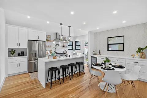 a kitchen with stainless steel appliances granite countertop a dining table chairs stove refrigerator and cabinets