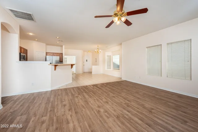 a view of empty room with wooden floor and ceiling fan
