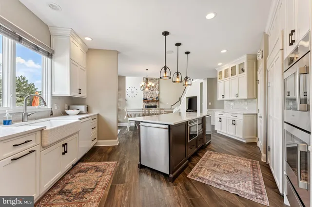 a large kitchen with stainless steel appliances kitchen island granite countertop a stove a sink dishwasher and a oven with white cabinets