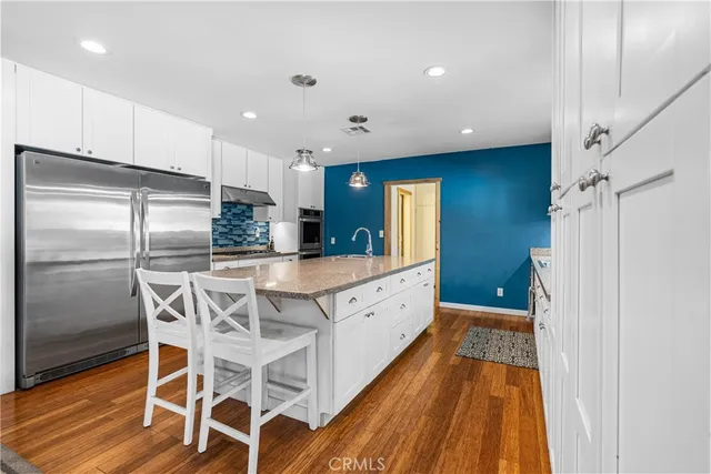 a kitchen with stainless steel appliances kitchen island granite countertop a refrigerator and a sink