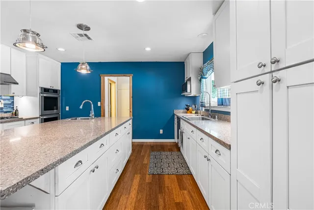 a large kitchen with granite countertop a sink and dishwasher a stove with wooden floor