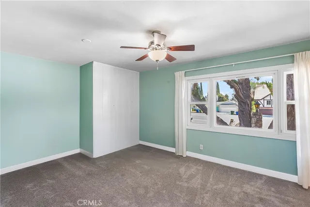 an empty room with windows and fan