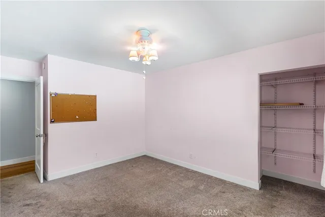 an empty room with a chandelier fan and wooden floor