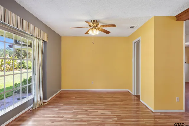 a view of empty room with wooden floor and fan