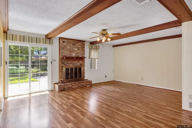 a view of a livingroom with wooden floor a ceiling fan and windows