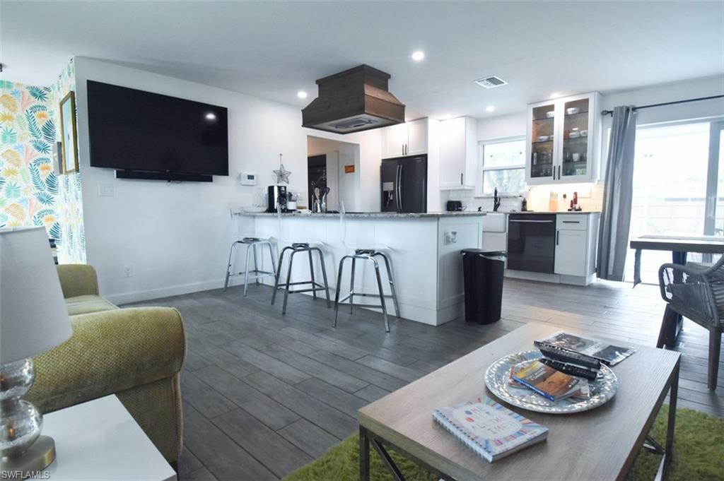 3131 Calusa Avenue Naples, FL 34112 - Photo 3 of 26 a living room with stainless steel appliances a dining table wooden floor and a kitchen view