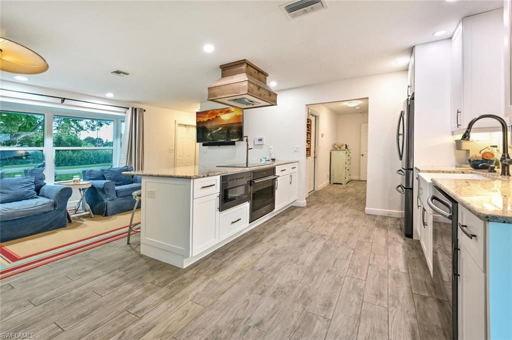 3131 Calusa Avenue Naples, FL 34112 - Photo 5 of 26 a kitchen with stainless steel appliances granite countertop a stove and a wooden floors