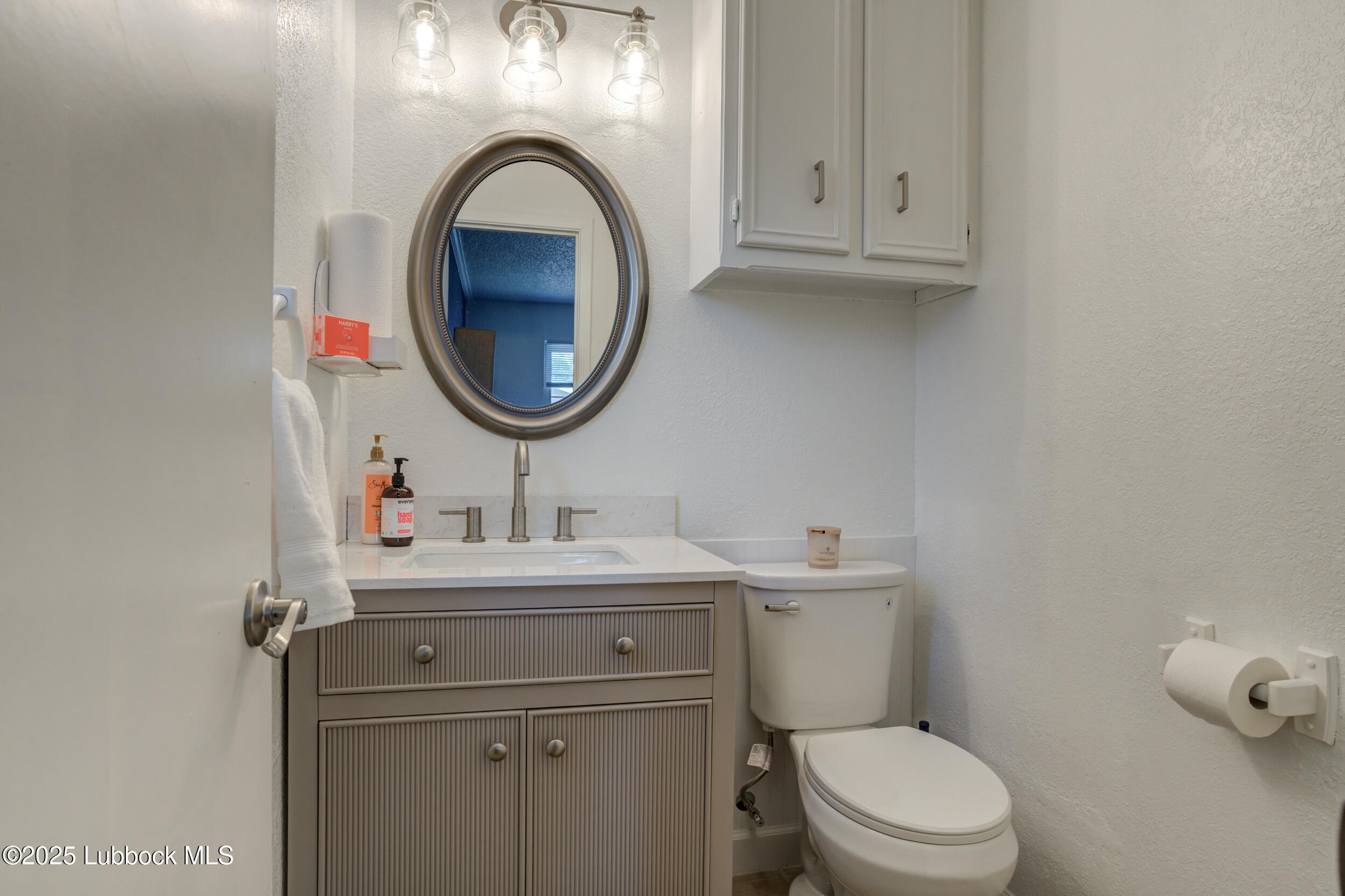 6403 28th Street Lubbock, TX 79407 - Photo 13 of 27 a bathroom with a toilet a sink and mirror