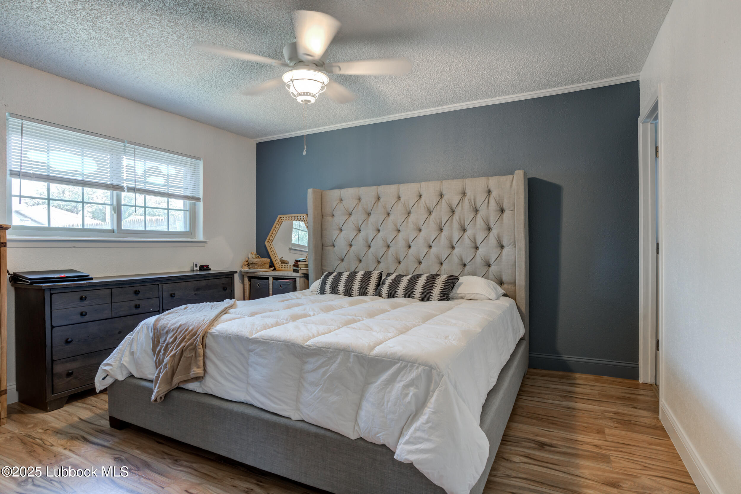 6403 28th Street Lubbock, TX 79407 - Photo 14 of 27 a bedroom with a large bed and a chandelier