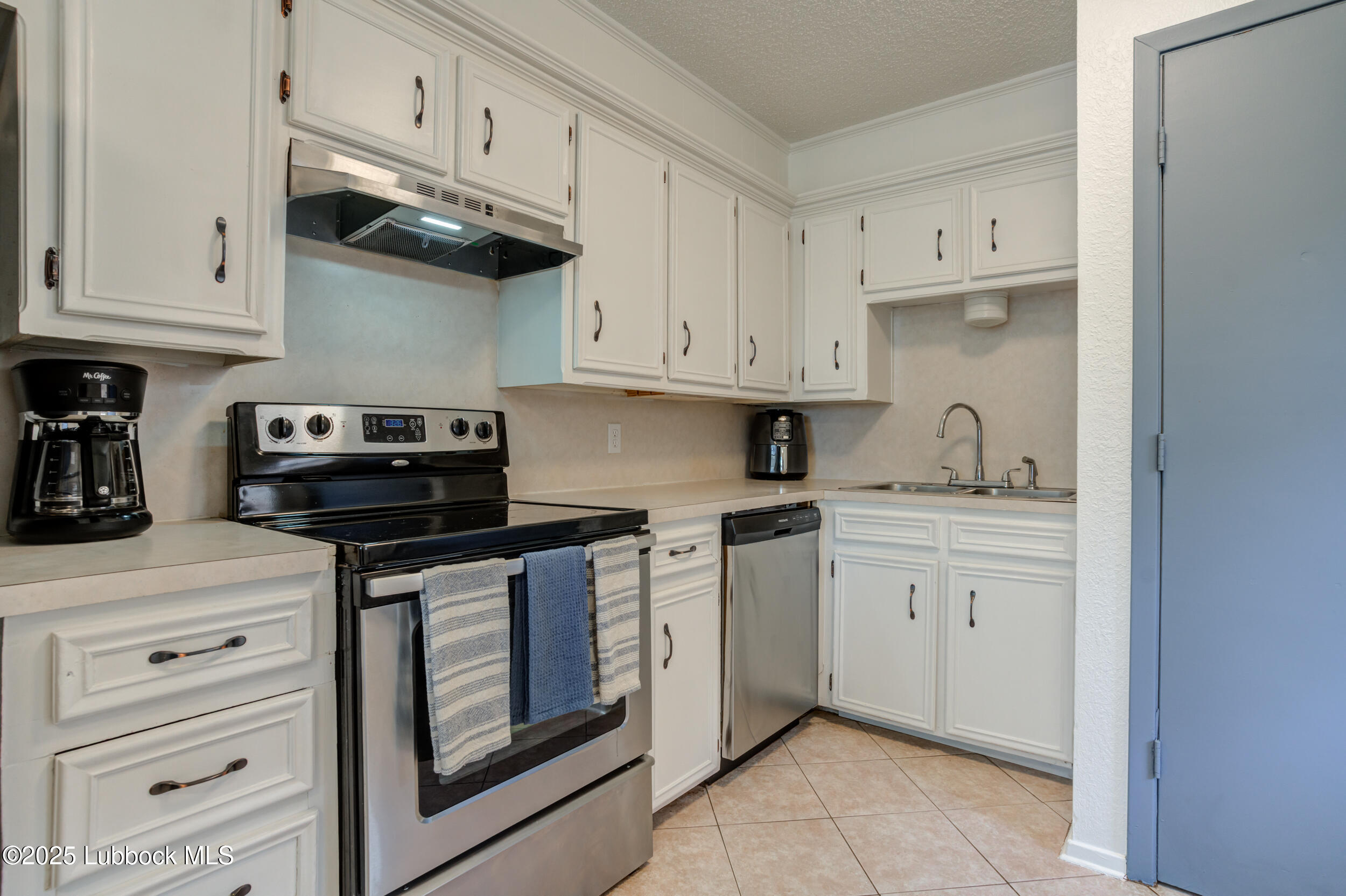6403 28th Street Lubbock, TX 79407 - Photo 7 of 27 a kitchen with white cabinets and appliances