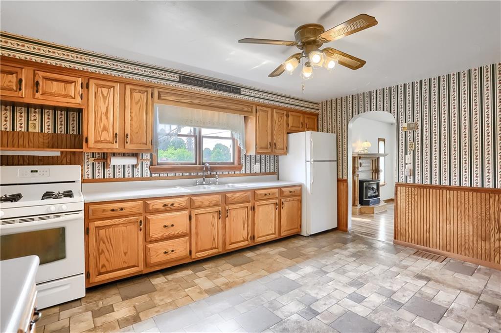 1081 Evans City Road Renfrew, PA 16053 - Photo 5 of 24 a large kitchen with granite countertop a stove a sink dishwasher a dining table and chairs with wooden floor