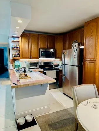 a kitchen with stainless steel appliances granite countertop a refrigerator a stove a sink a dining table and chairs