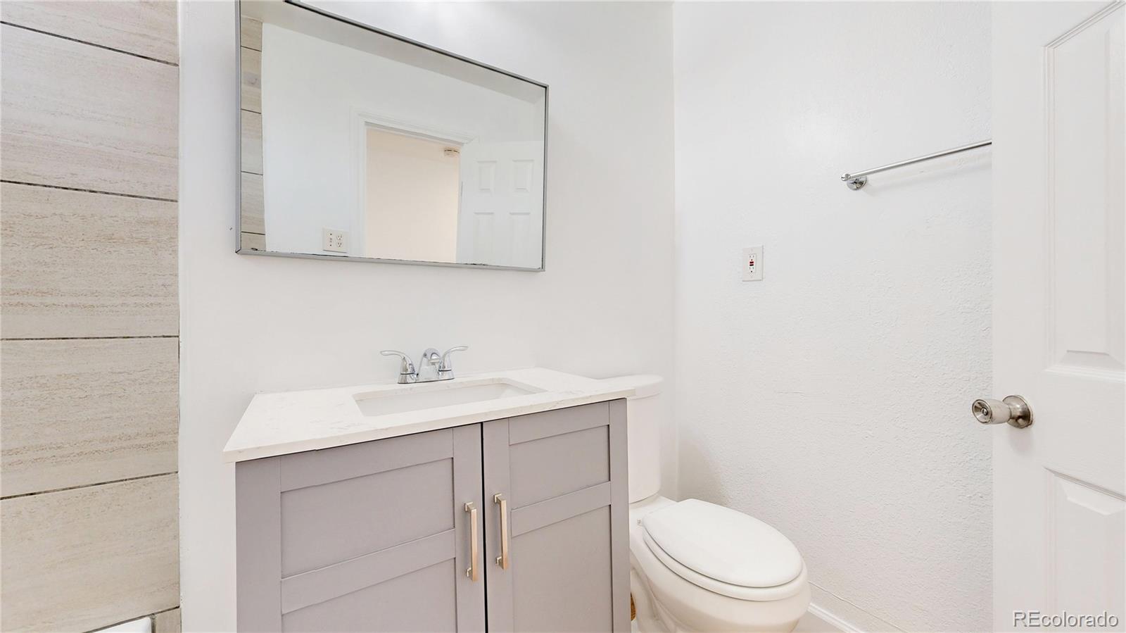 345 South Utica Street Denver, CO 80219 - Photo 10 of 19 a bathroom with a toilet a sink a mirror and vanity