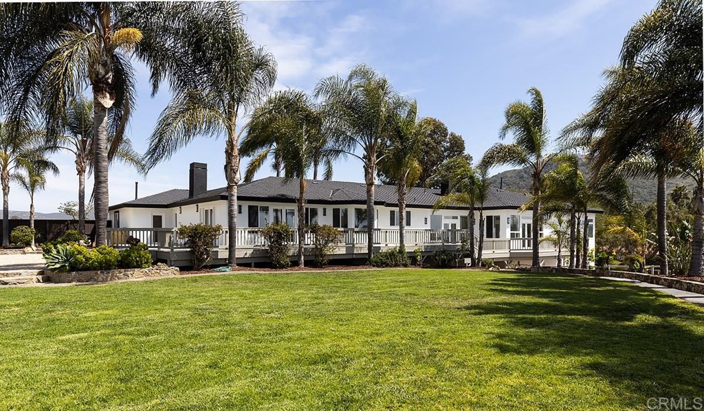 6949 Elfin Oaks Road Escondido, CA 92029 - Photo 23 of 24 a row of palm trees and a yard in front of the house