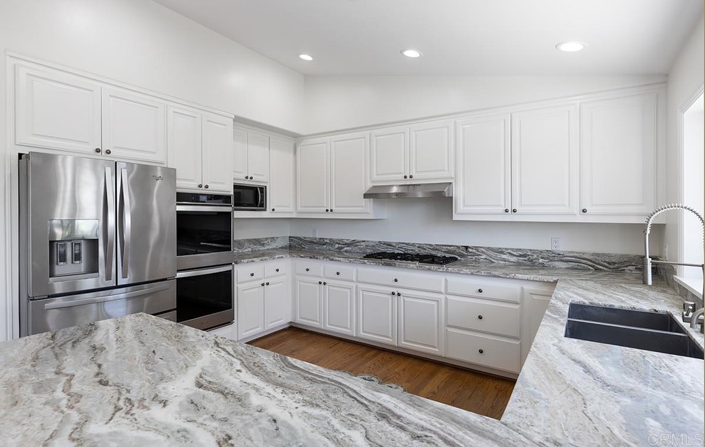 6949 Elfin Oaks Road Escondido, CA 92029 - Photo 6 of 24 a kitchen with granite countertop a refrigerator sink and white cabinets