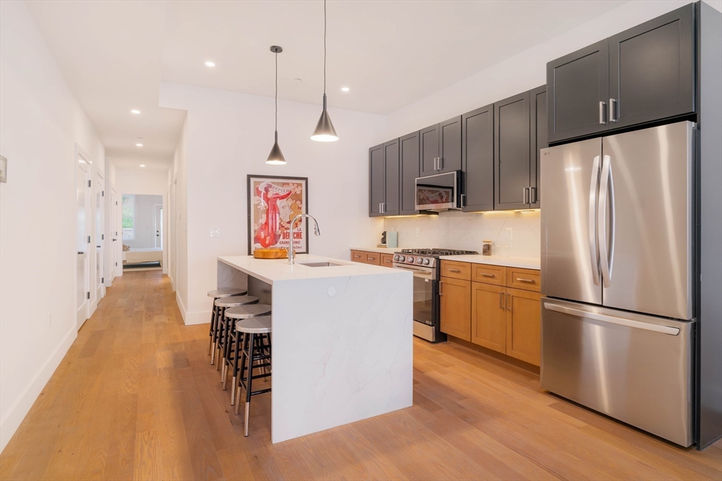 231 Everett Street, Unit 1 Boston, MA 02128 - Photo 2 of 25 a kitchen with a refrigerator a stove top oven a sink and a center island