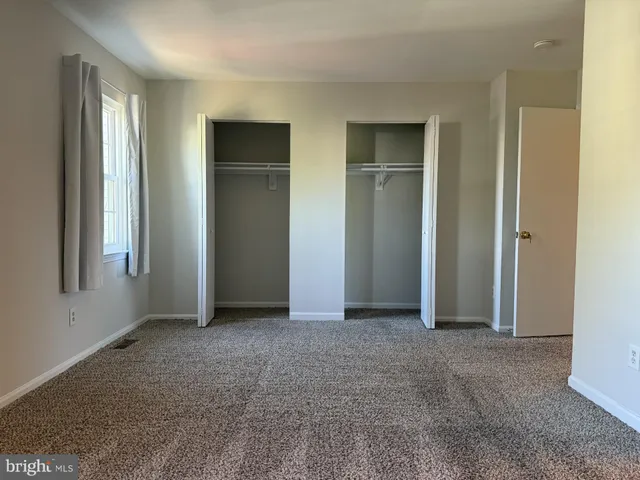 a view of an empty room with closet and a window