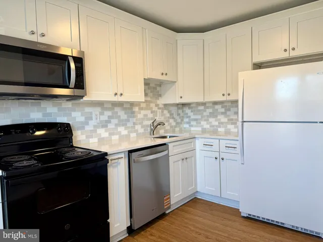 a kitchen with stainless steel appliances white cabinets and a stove top oven