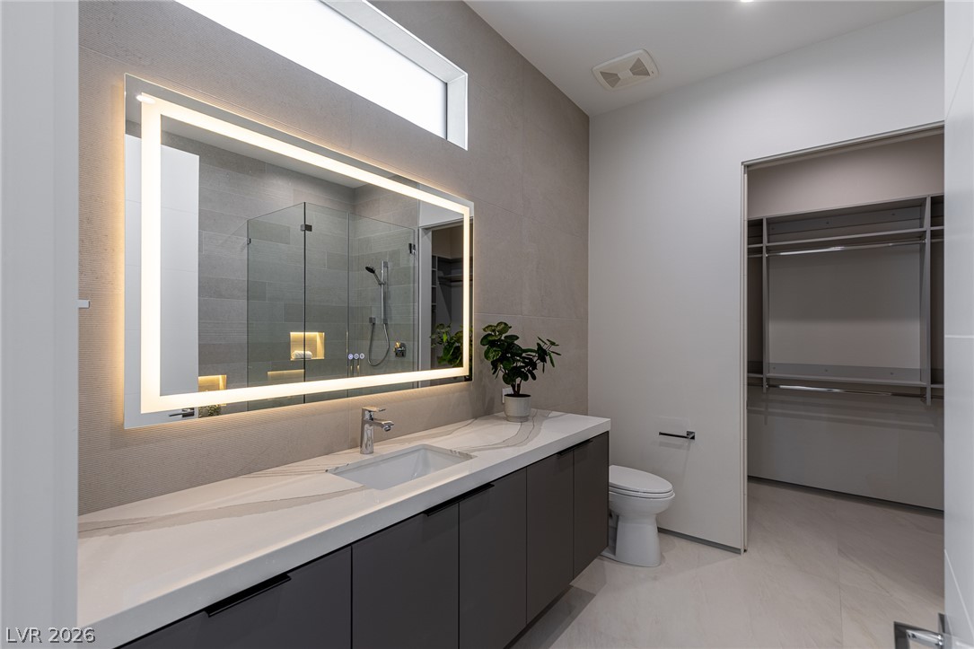 563 Grand Rim Drive Henderson, NV 89012 - Photo 39 of 70 A well-appointed bath features a luminous mirror, sleek vanity, and a generously sized walk-in closet.