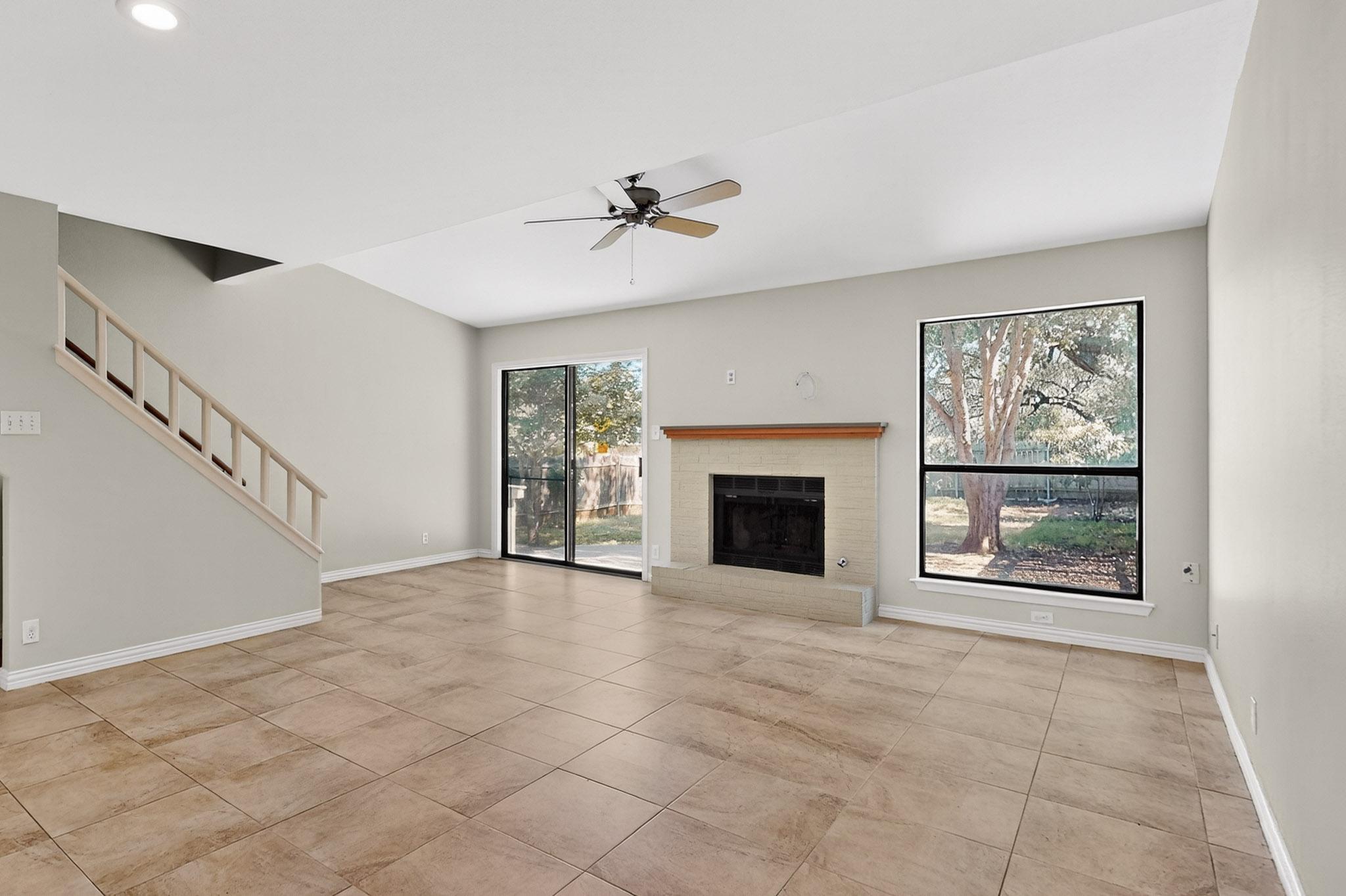 6023 Old Fredericksburg Road, Unit A Austin, TX 78749 - Photo 3 of 29 A spacious living area featuring tiled flooring, a cozy fireplace and large windows inviting abundant natural light.