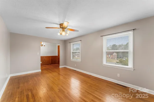 a view of an empty room with window and wooden floor