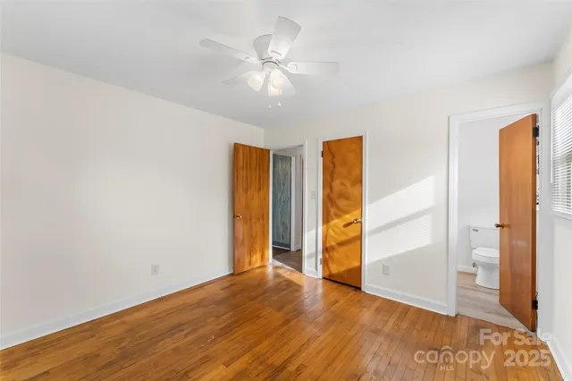 an empty room with wooden floor cabinet and windows