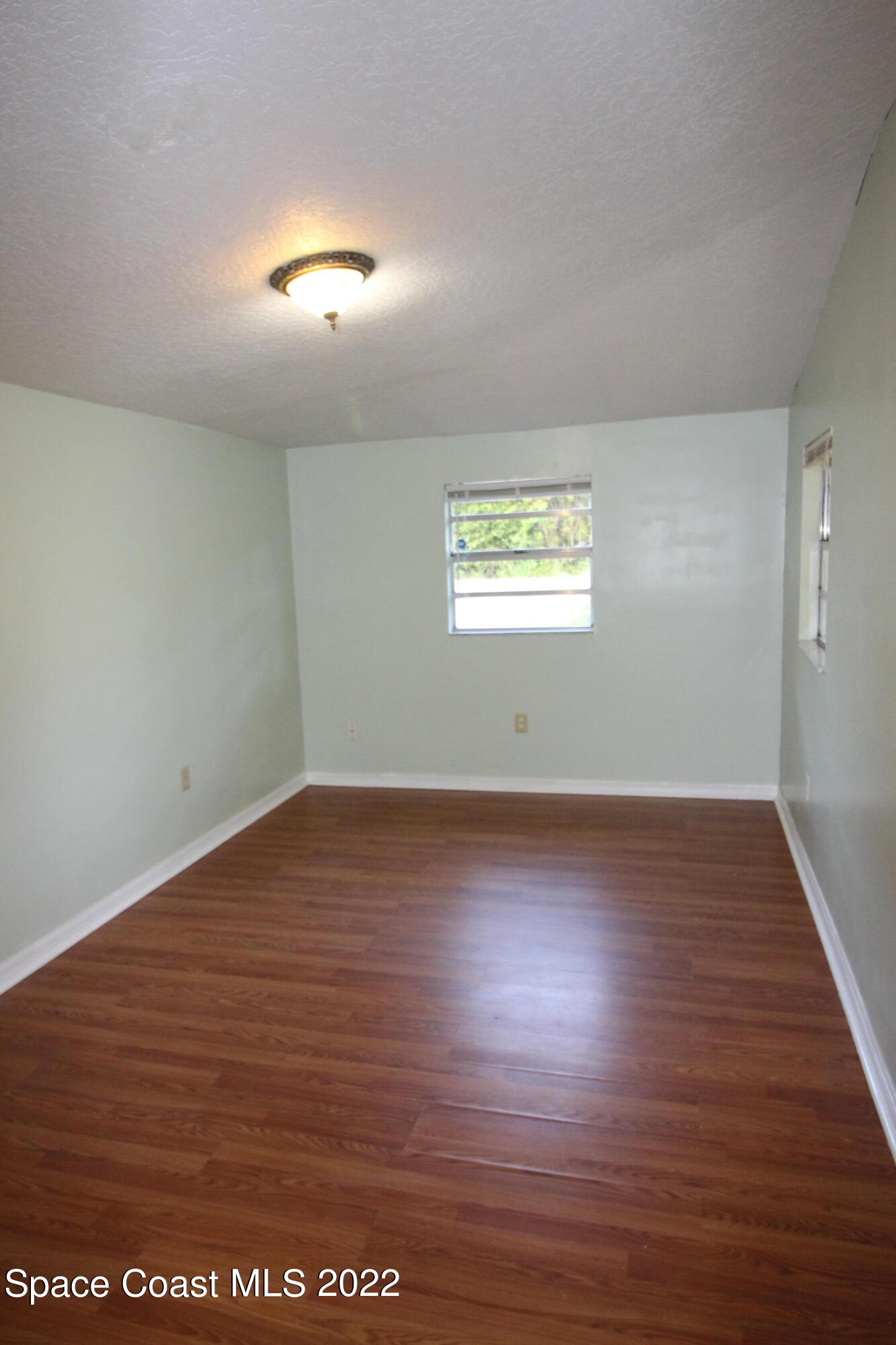 525 North Burnett Road Cocoa, FL 32926 - Photo 7 of 14 an empty room with wooden floor and windows