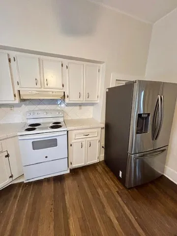 a view of an empty room with wooden floor and windows