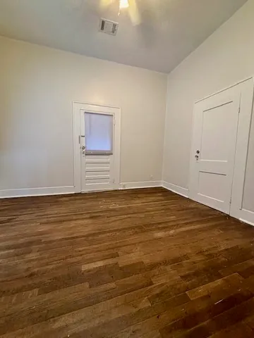 a view of an empty room and wooden floor and a window