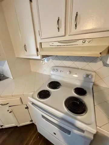 a kitchen with stainless steel appliances a stove a refrigerator cabinets and wooden floor