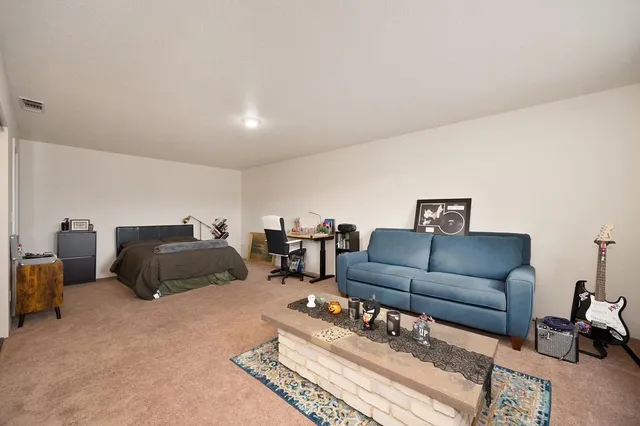 a living room with a bed furniture flat screen tv and a large window